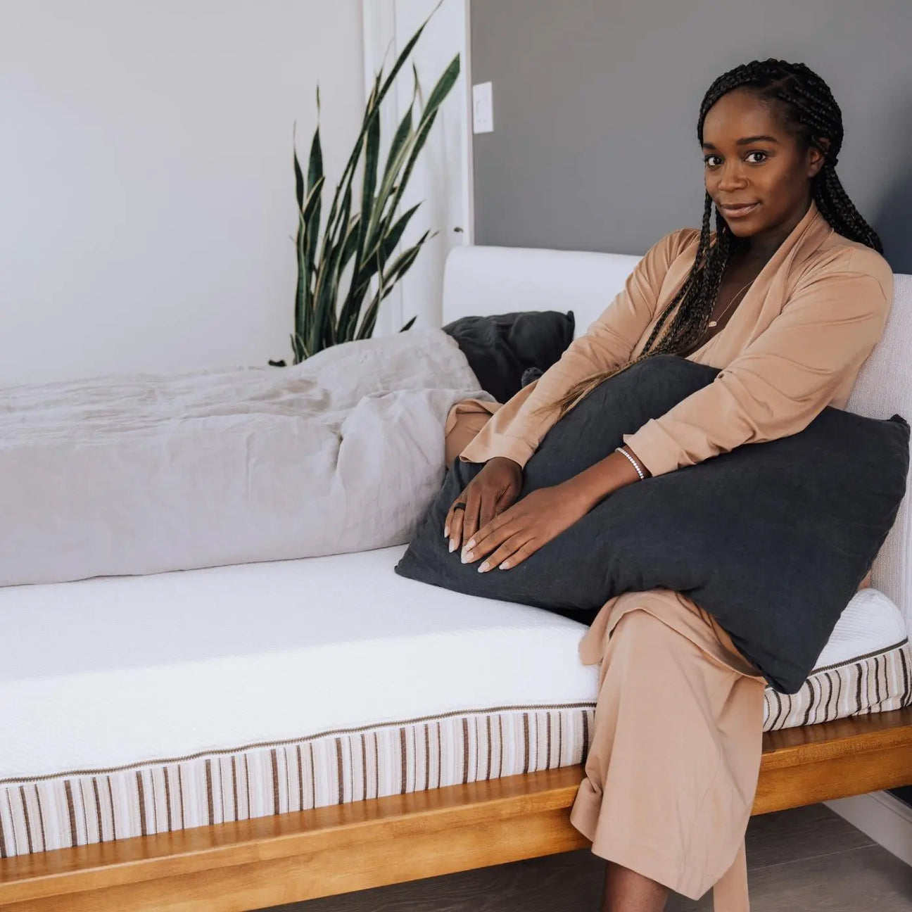A woman sitting on an Essentia mattress holding a pillow